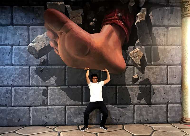 Me struggling to hold up what looks like a massive foot over my head but the foot is actually a wall painting